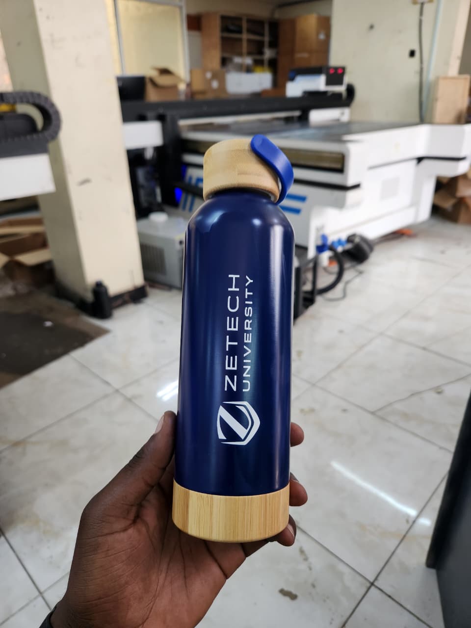 Laser engraved flask in Nairobi by Almasi Prints, a Zetech University logo engraved through the blue coating of a steel vacuum bottle